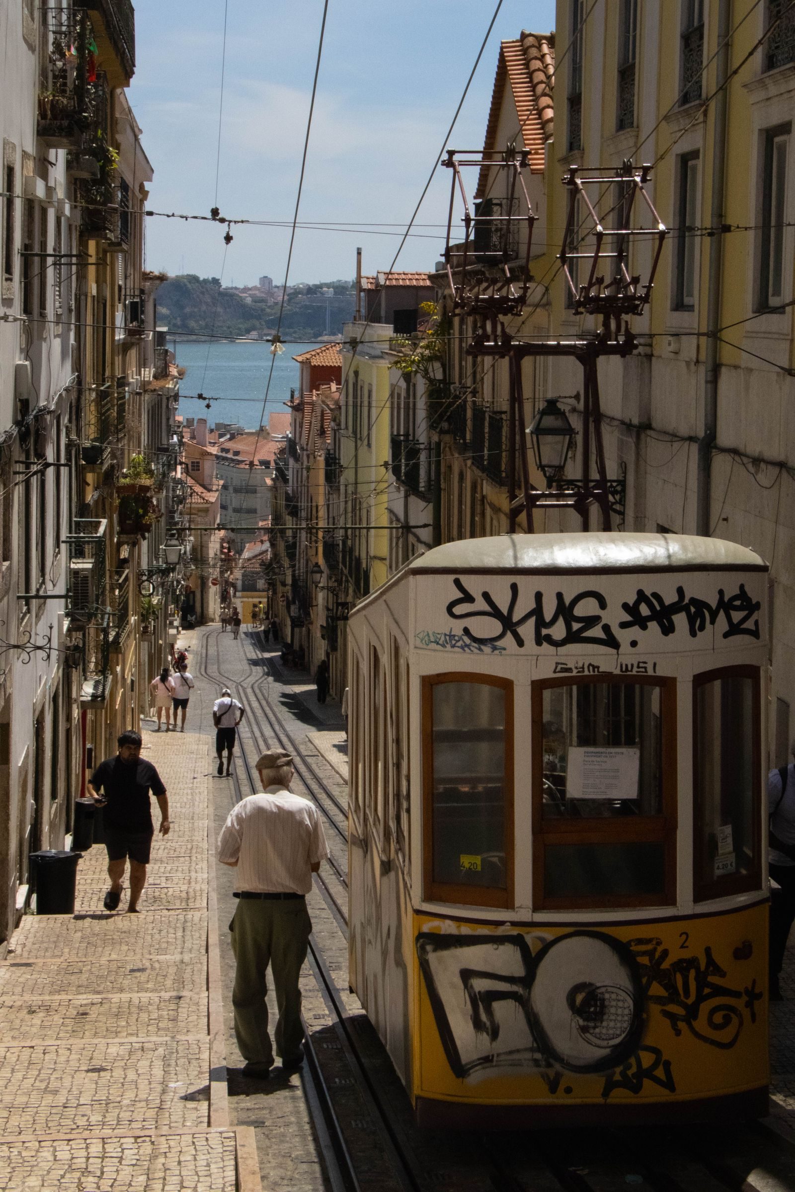 A tram climbing through Bairro Alto in Lisbon, with the river behind