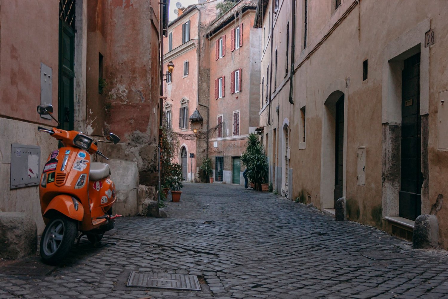 A cobbled lane with an orange scooter in Trastevere, Rome