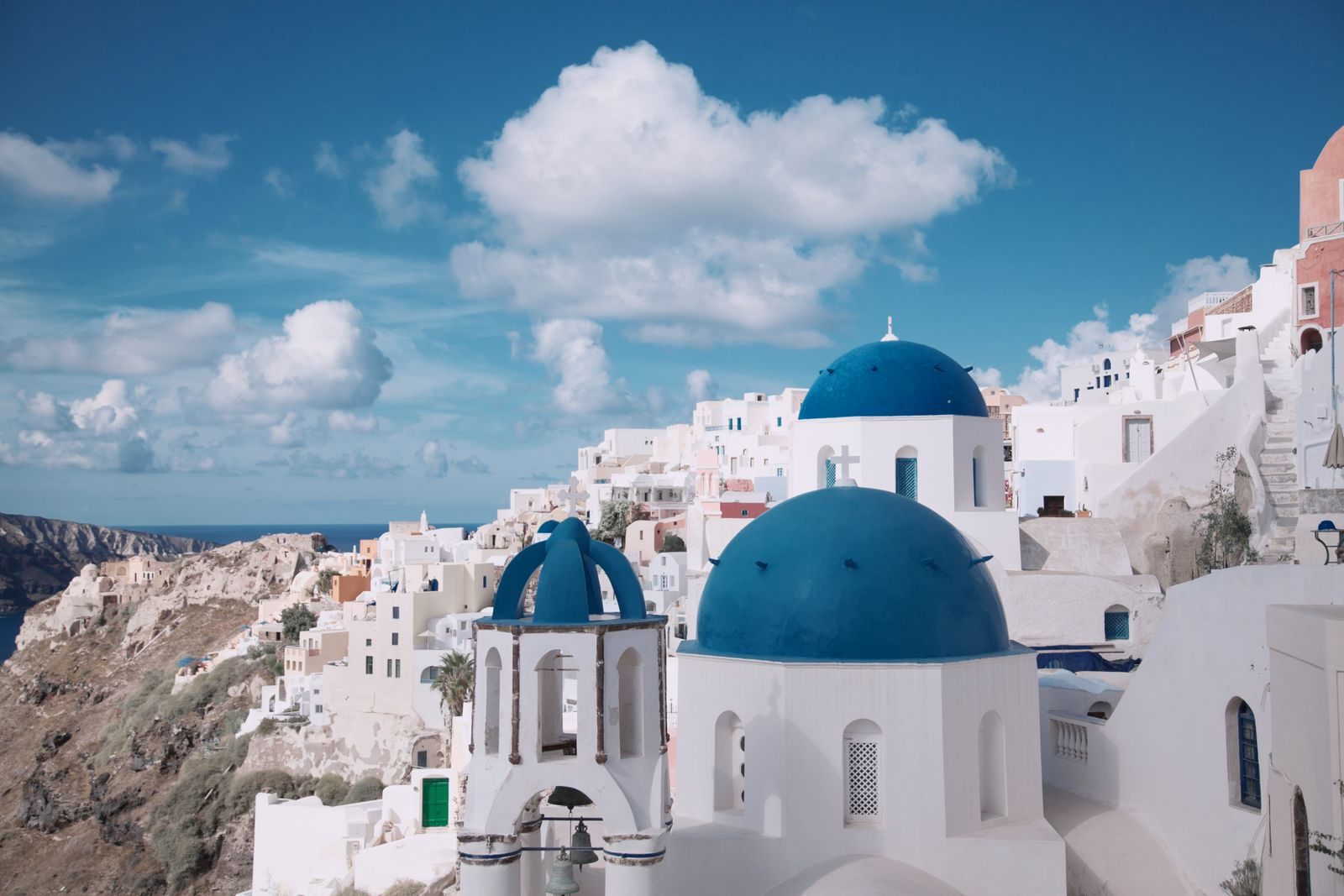 The blue-domed churches of Oia, Santorini, above the Aegean Sea.