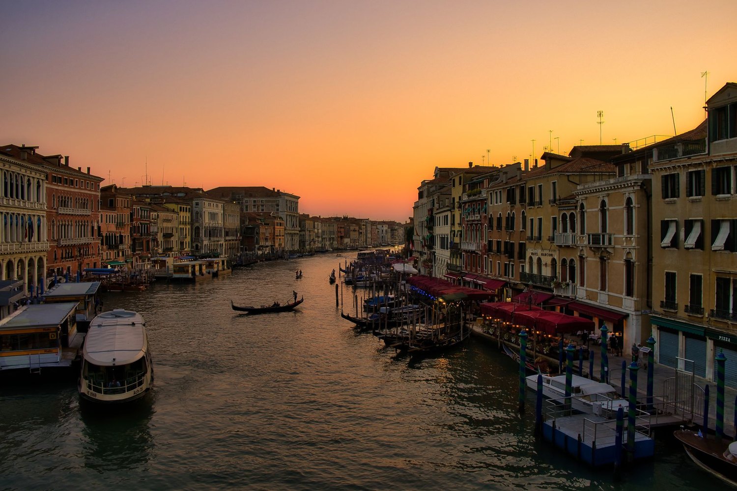The Grand Canal in Venice at sunset, lined with boats and palaces.